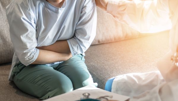 Woman sitting on the couch holding her stomach