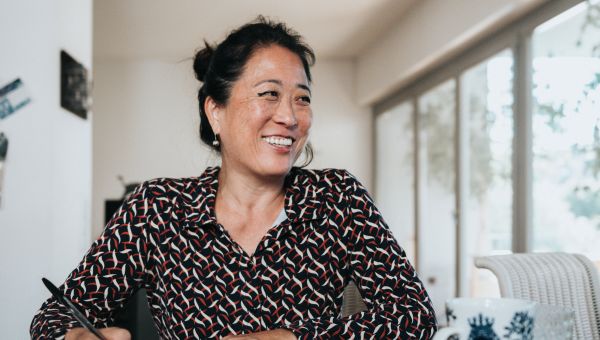 smiling mature Asian person sitting at table