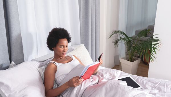 Black person lying in bed reading