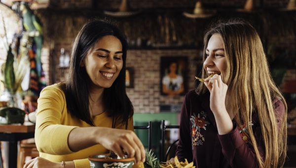 a pair of female friends enjoys eating chips and guacamole at a Mexican restaurant