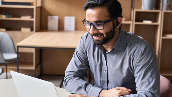 Man with glasses on a laptop helping someone decide on health insurance.