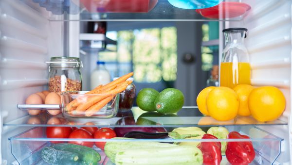 an interior photograph of a refrigerator stocked with healthy foods including fresh fruits and vegetables 