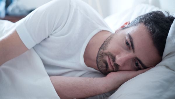 A depressed man laying in bed, unable to start his day