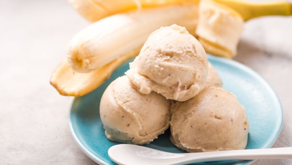 a bowl of frozen dessert made with blended bananas, accompanied by a fresh banana