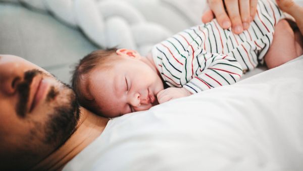 an infant sleeps on its father's chest