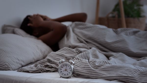 woman in bed with clock can't sleep