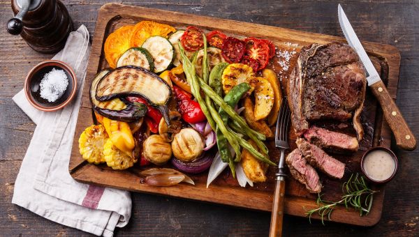 A cutting board filled with paleo-friendly foods, including plenty of vegetables and protein.