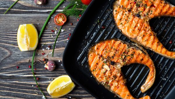 Salmon steaks on the grill with some lemon and herbs, a staple of any paleo diet.