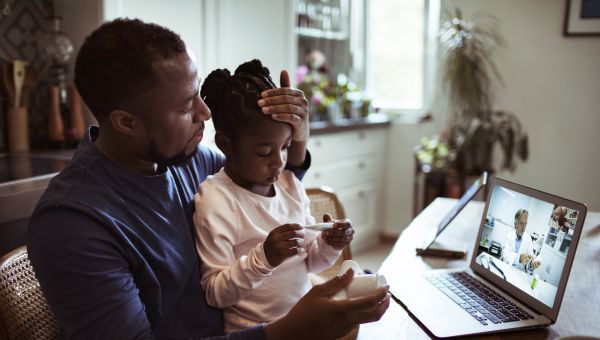 father and child with fever video conferencing with provider