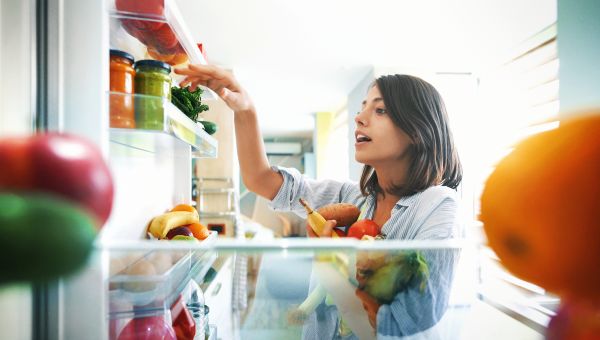 woman taking vegetables from refrigerator
