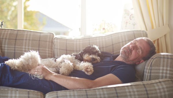 man sleeping on couch with dog