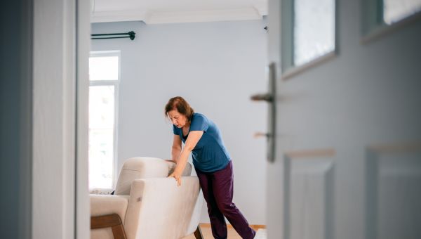 senior woman losing balance leaning on couch for support