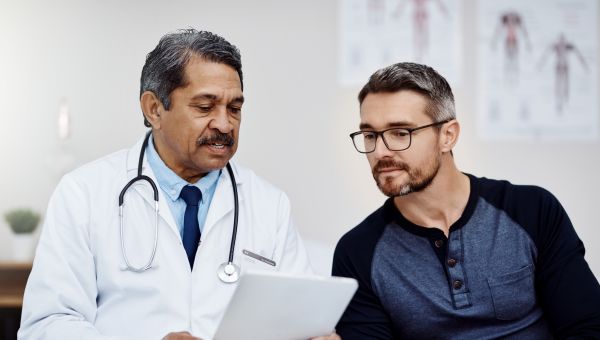 Latino male doctor consulting with a middle aged male white patient