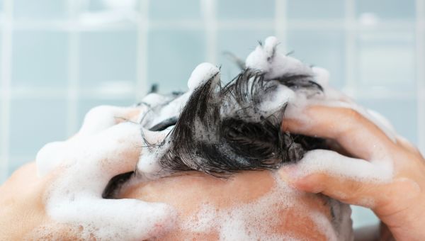 closeup of man lathering washing hair in shower