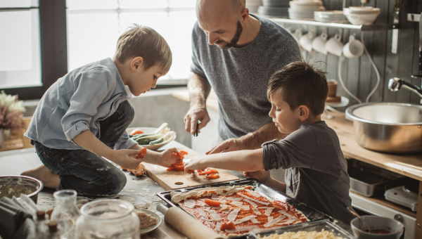 boy with autism and his brother help their dad make pizza in a messy kitchen