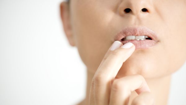 woman touching a sore on her mouth