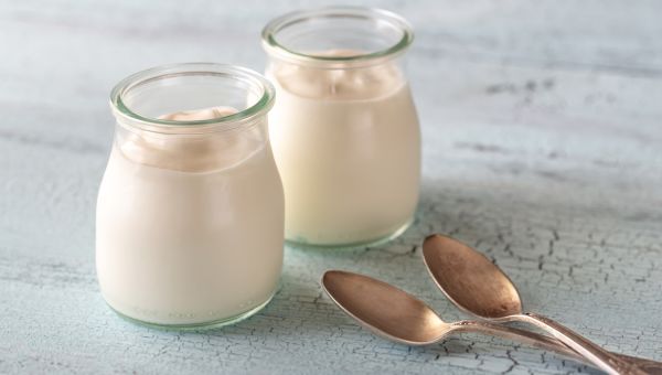 two glass pots of greek yogurt with spoons