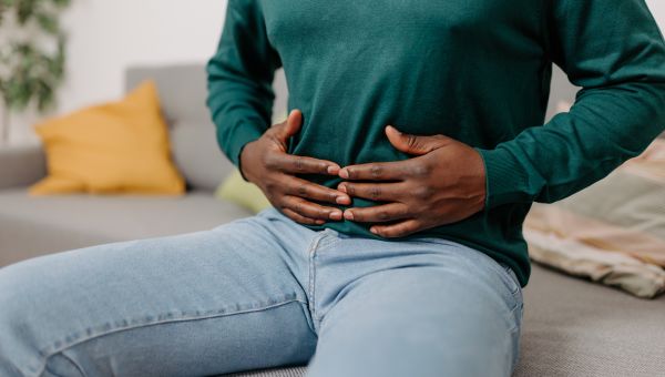 young man sitting on couch with hands on stomach
