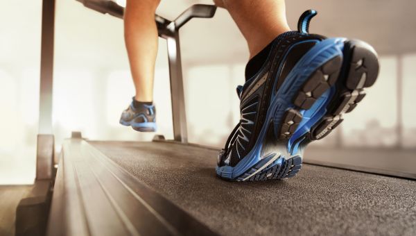 close up of tennis shoe-clad feet running on a treadmill indoors