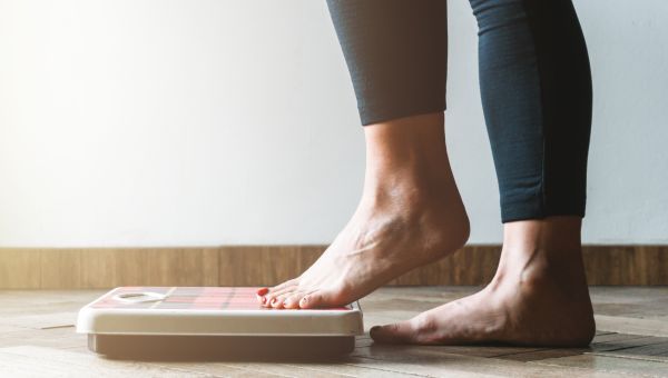 Woman weighs herself on scale.