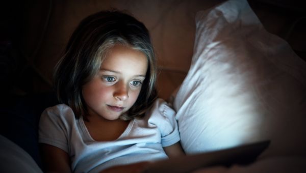 child looking at tablet in bed