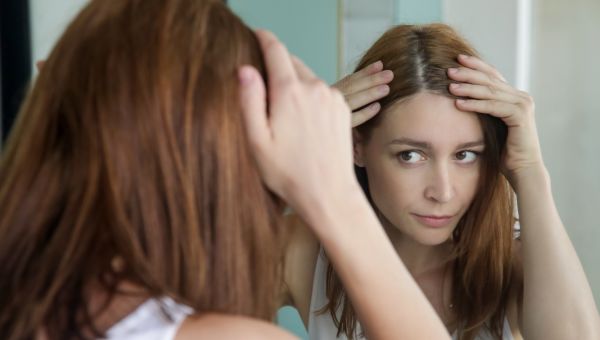 woman checking scalp in a mirror