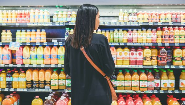 woman looking at juice on shelves at market