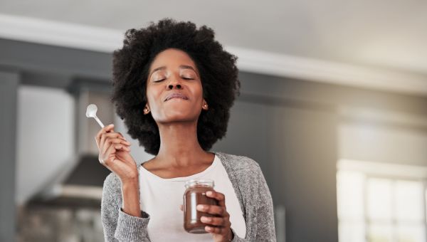 a young Black woman enjoys a jar of chocolate pudding