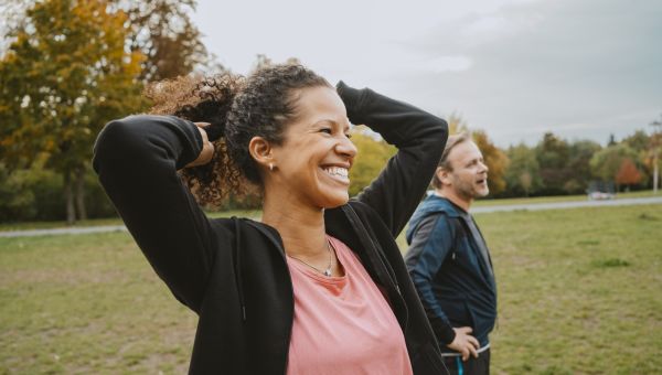 a middle aged Latina woman smiles and walks in a park with a male friend