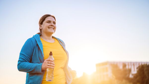 Happy curvy african woman doing workout routine outdoor at city park