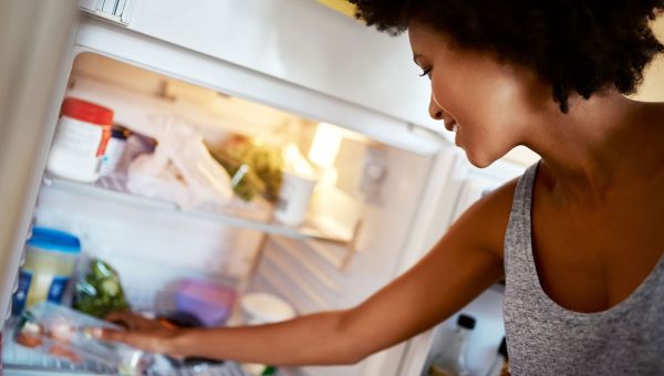 Woman reaching into fridge for snack