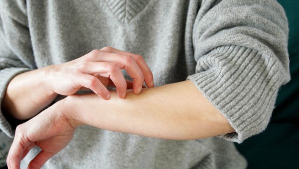 closeup image of a person holding up their arm and scratching it 