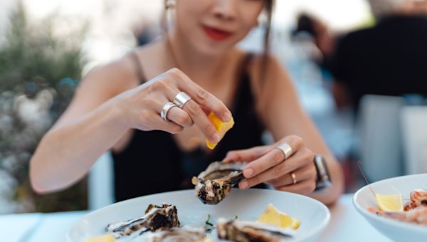 woman squeezing lemon juice on oysters