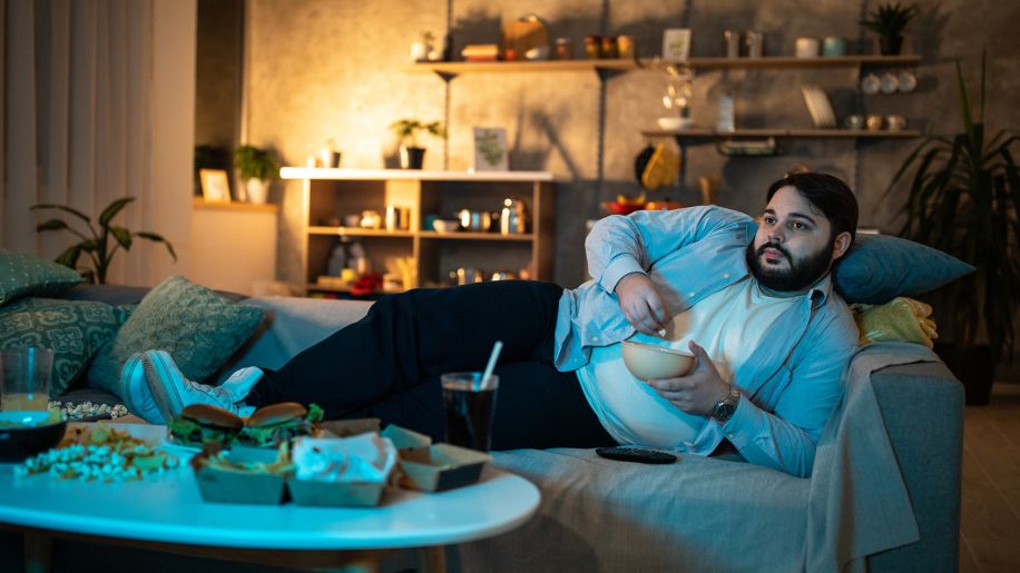 man eating junk food on the couch