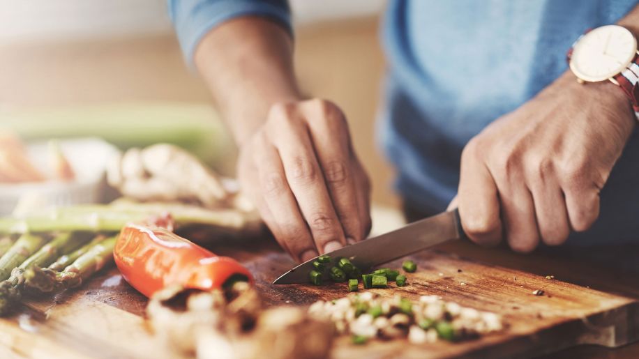 Man chopping up vegetables with a small knife.