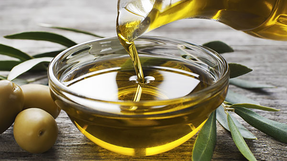 Olive oil being poured into a glass bowl.