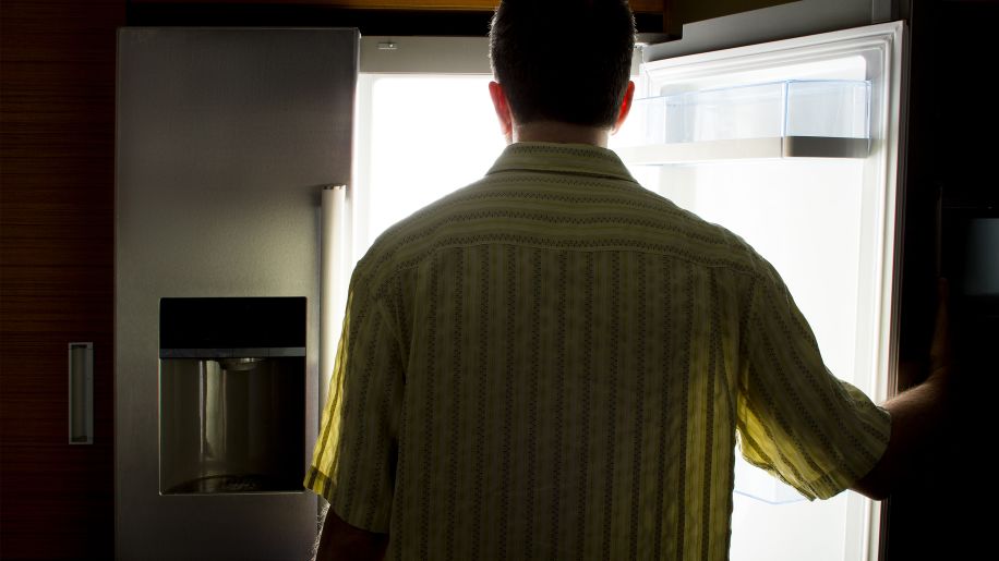 Man opening refrigerator at night