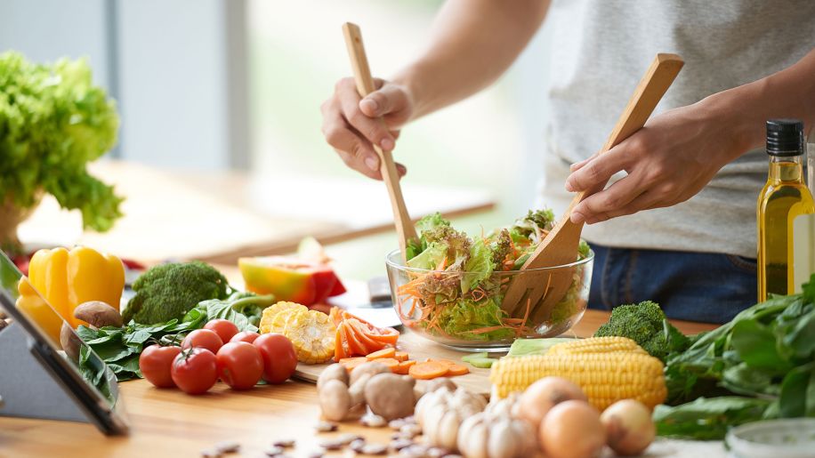 A salad is prepared in a bowl with vegetables placed on the table.