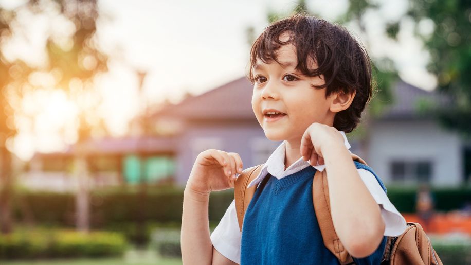 a healthy, happy vaccinated child with a backpack standing outside