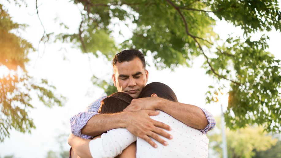 father hugging teen daughters