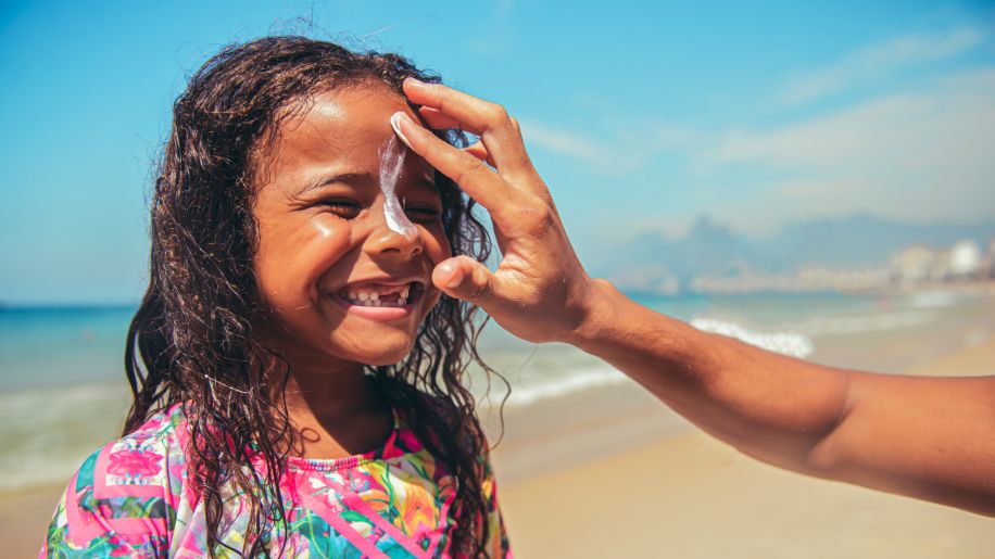 Mom applying sunscreen lotion on daughter's face