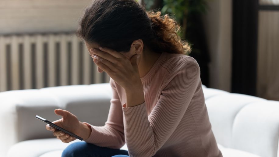 depressed woman at home looking at phone