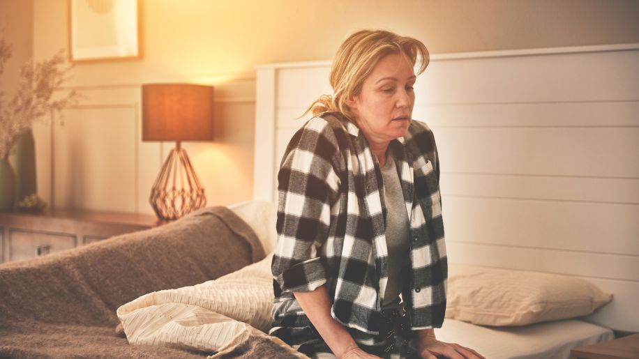 tired young woman sitting on edge of bed