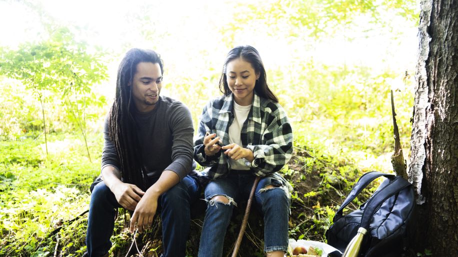 two people taking a break from hiking in nature while one of them check their blood sugar level
