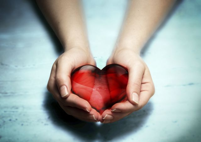 two hands holding red crystal heart