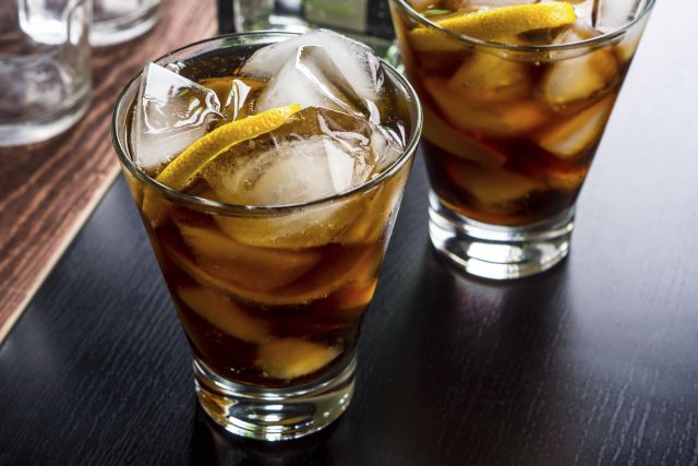 Cola with lemon slice in glass on wooden table