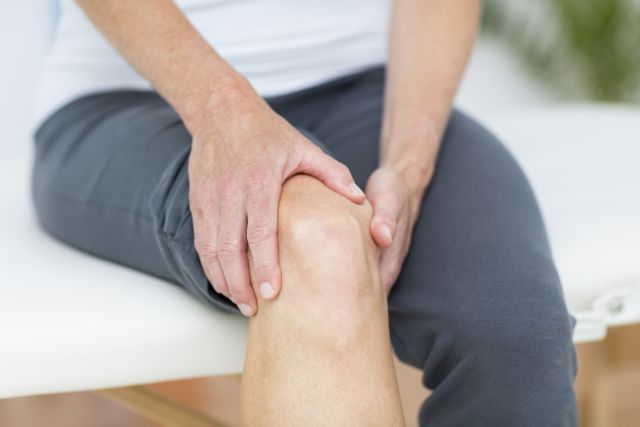 A man with rheumatoid arthritis (RA) rubs his knee—feeling muscle weakness from a condition called rheumatoid cachexia.