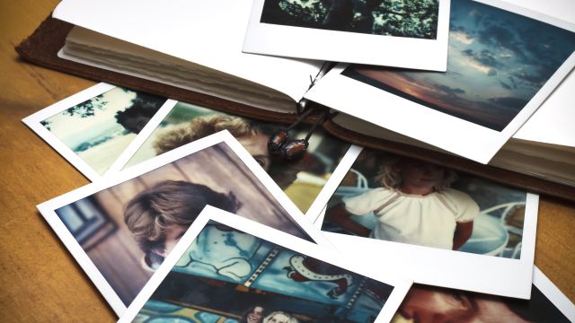 wooden table with a photo album and polaroid photographs