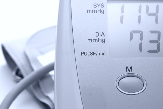 Detail of a digital blood pressure and heart rate monitor with arm band. Blue-tinted monochrome image.