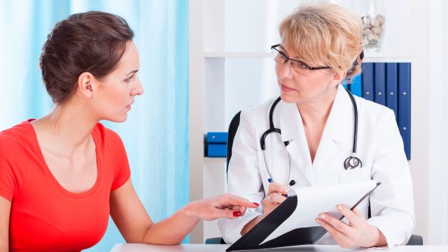 A woman with rheumatoid arthritis symptoms sees her doctor to discuss symptoms and when she should see a rheumatologist. 